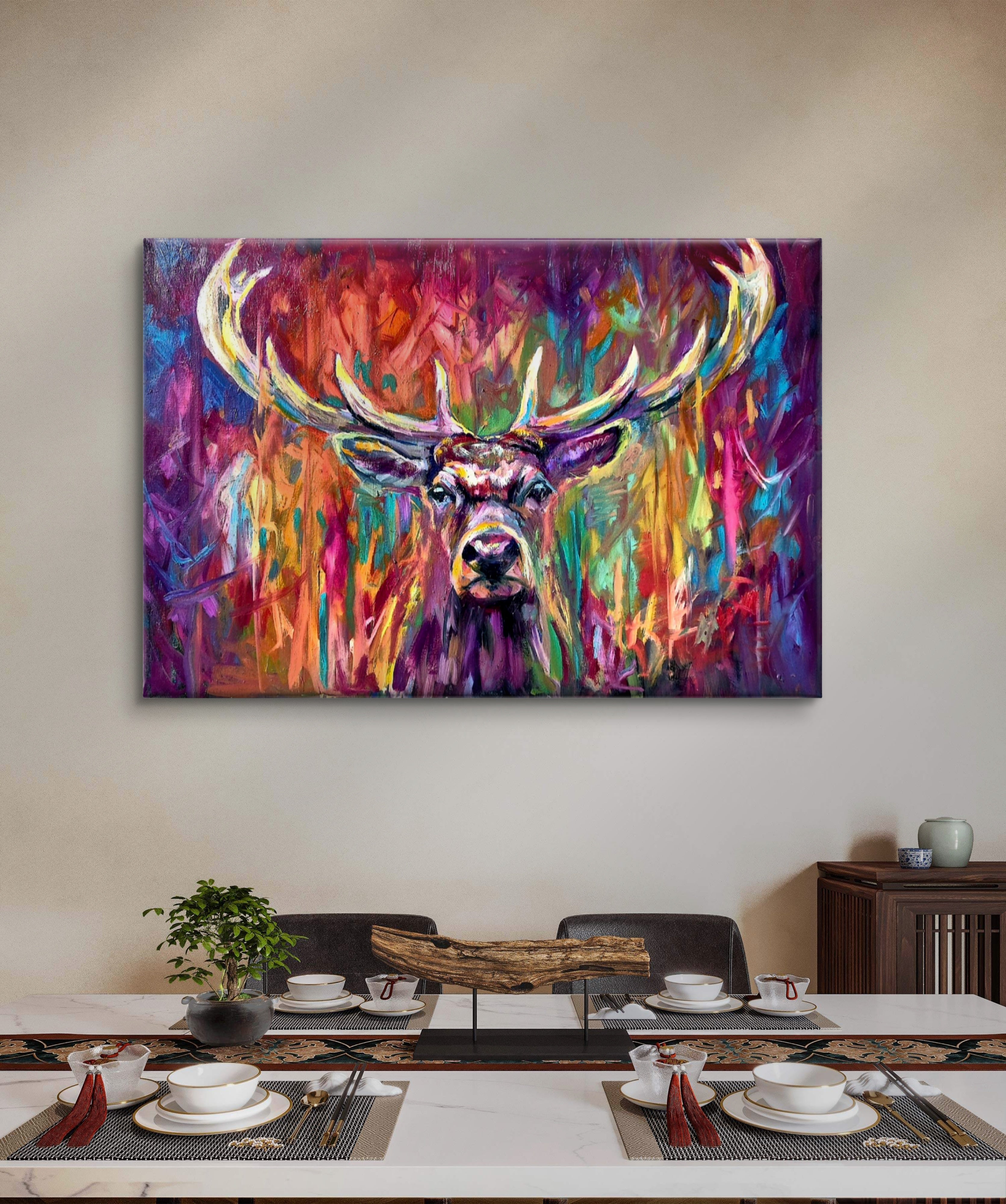 Colorful abstract painting of a deer head on a wall above a dining table.